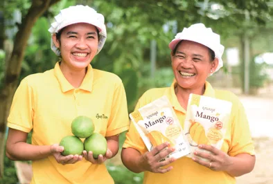 Two farmers holding mangoes and packs